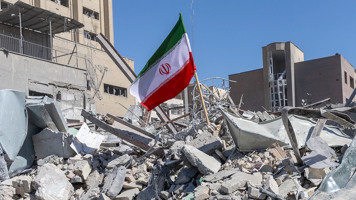 Iranian flag standing atop rubble