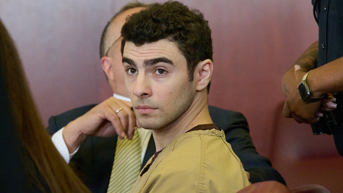 Luigi Mangione seated in court as judge drops terrorism charges.