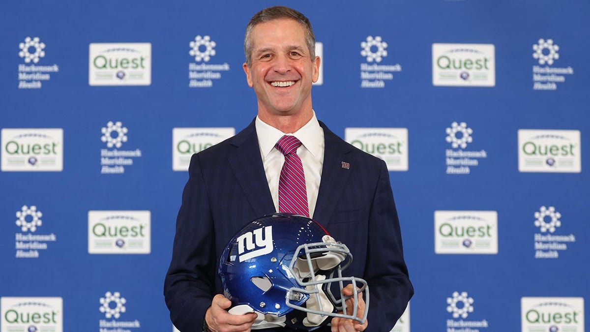 John Harbaugh with a Giants helmet