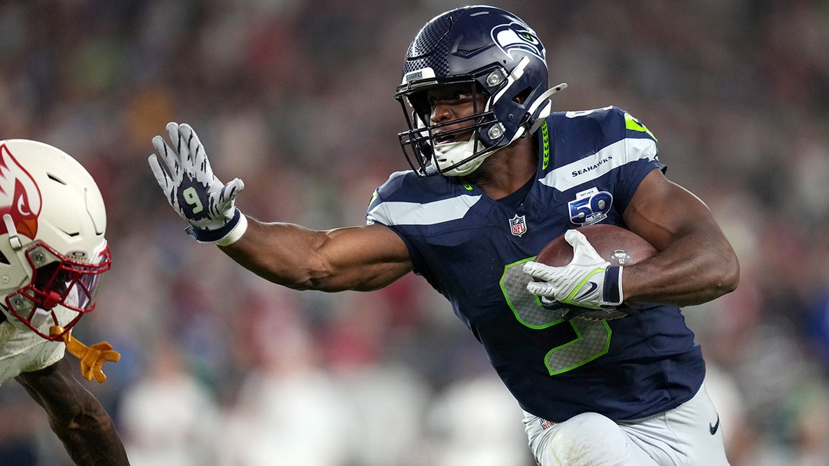 Kenneth Walker delivers a stiff arm