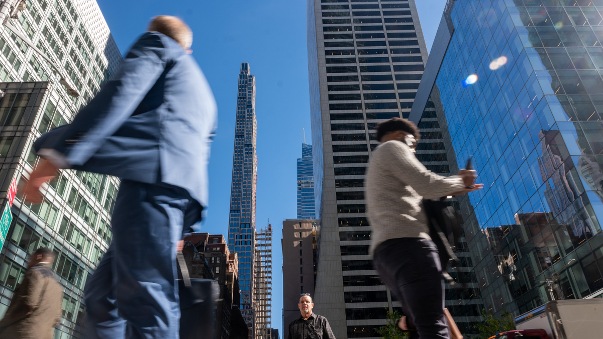 People are seen walking across the street in New York City.