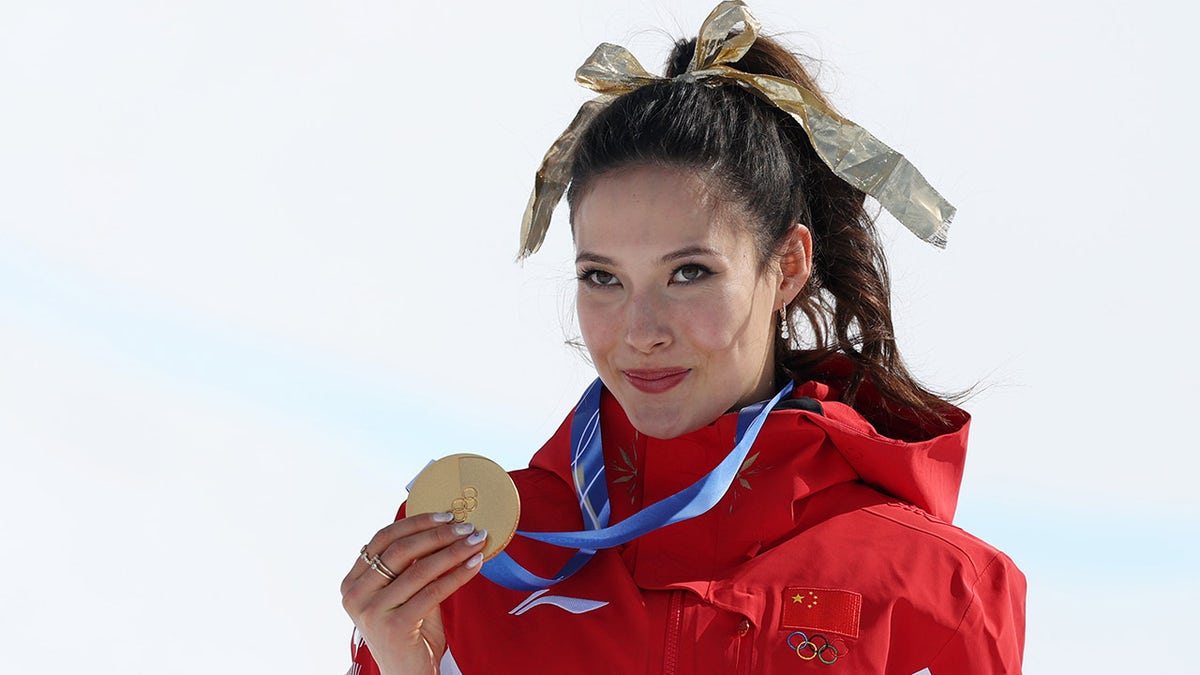 Eileen Gu holds up the gold medal