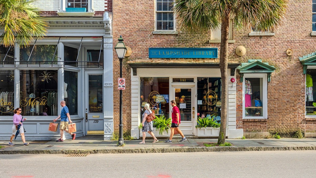 People walking on the sidewalk by the shops in Charleston, South Carolina.