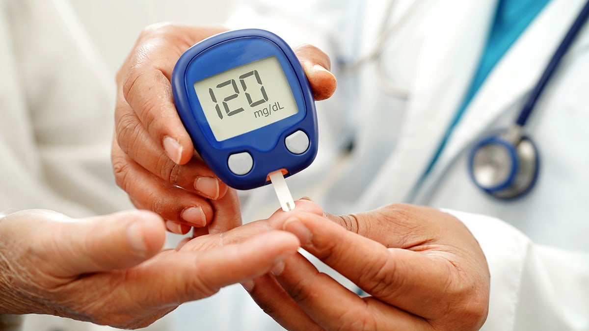 Doctor using digital glucose meter for check sample blood sugar level to treatment diabetes.