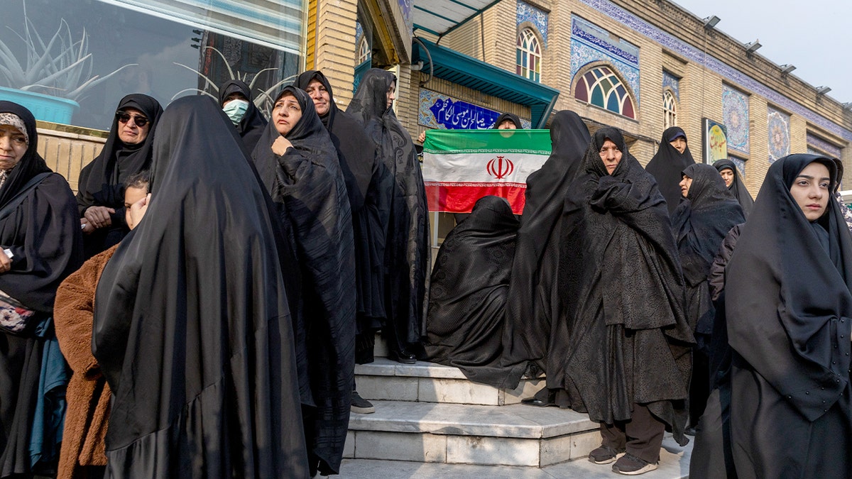 A woman holds an Iranian flag during a funeral ceremony at the Imamzadeh Saleh shrine in Tehran.
