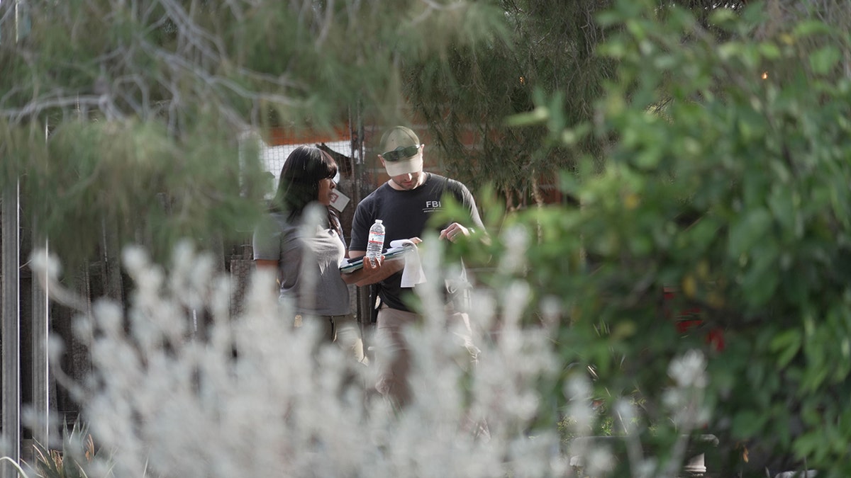 Investigators walking past houses and through a neighborhood in search of Nancy Guthrie
