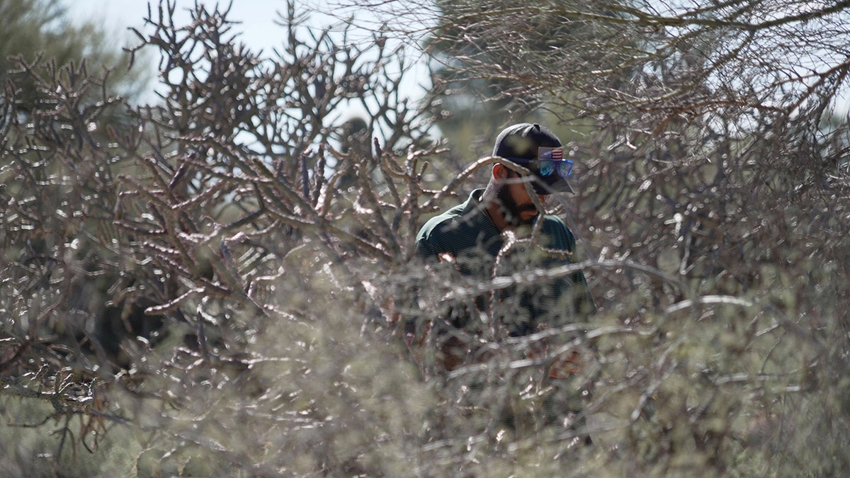 An investigator searching the grounds near Nancy Guthrie's property in the Catalina Foothills.