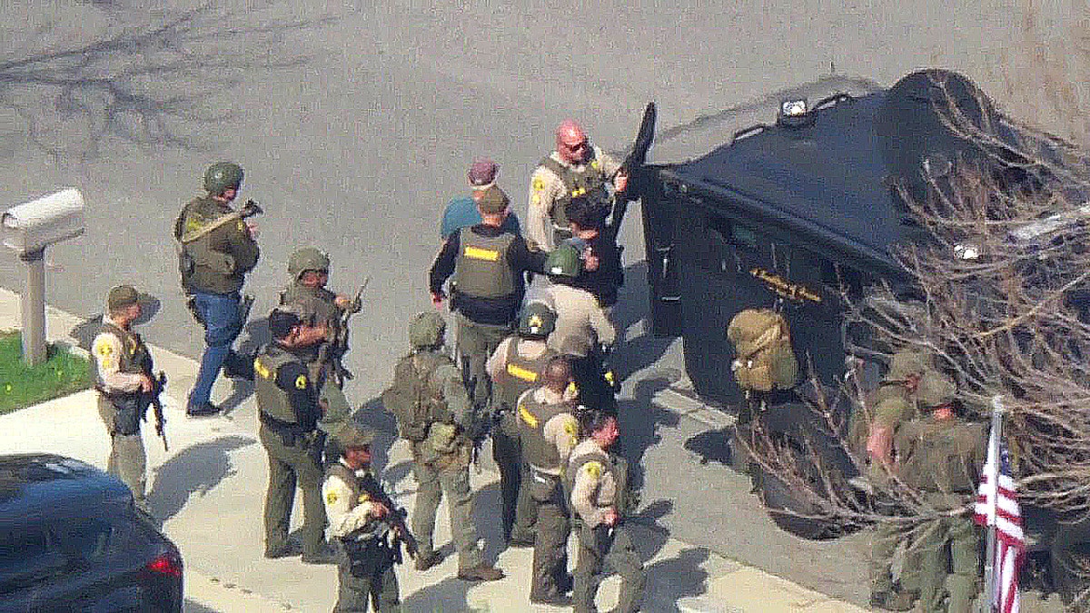 swat members surround tactical vehicle in neighborhood with suspect