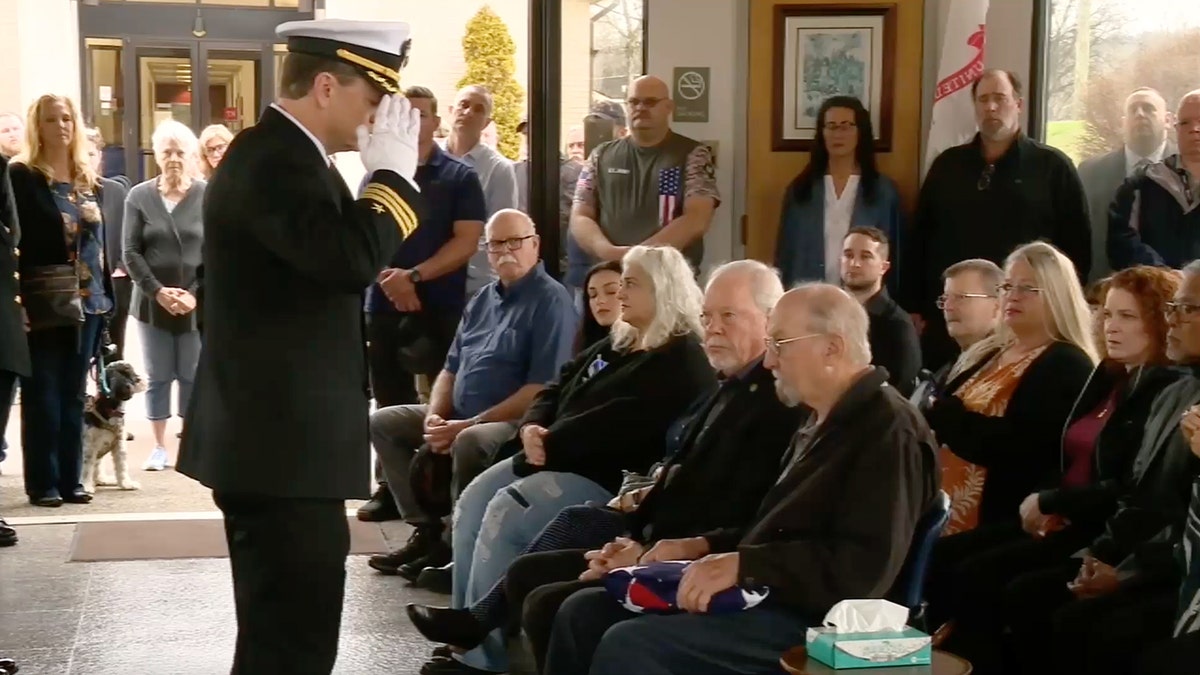 A Navy official salutes an audience member in the crowd