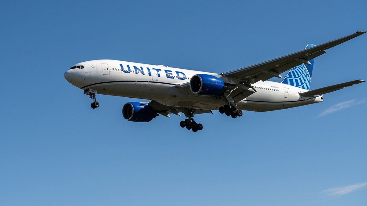United Airlines plane flying in the blue sky.