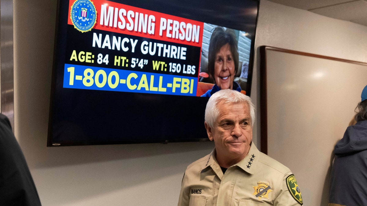 Pima County Sheriff Chris Nanos exiting press room near missing persons poster
