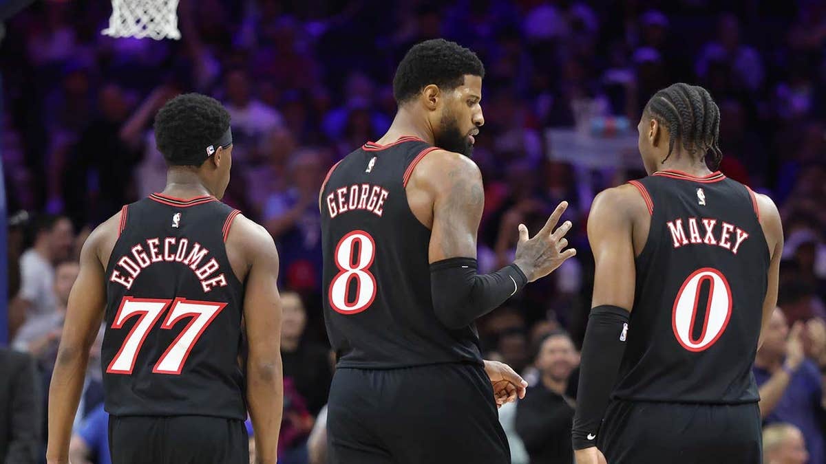 Philadelphia 76ers forward Paul George talking with guards Tyrese Maxey and Vj Edgecombe on the court