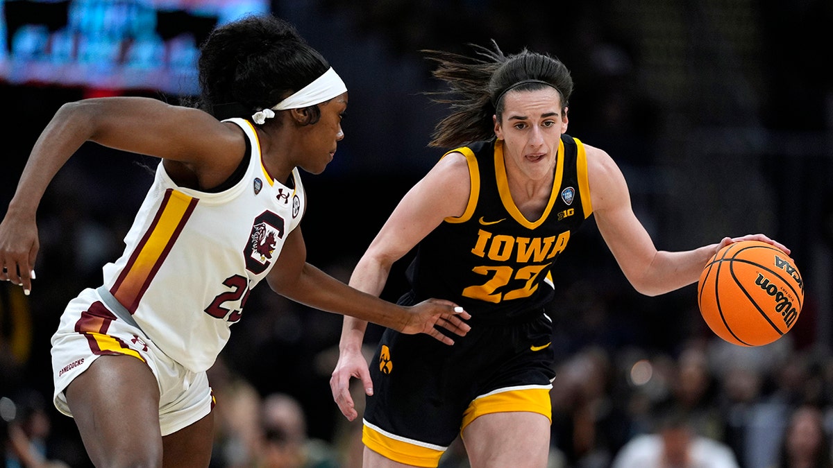 Iowa guard Caitlin Clark drives up court past South Carolina guard Raven Johnson during a basketball game