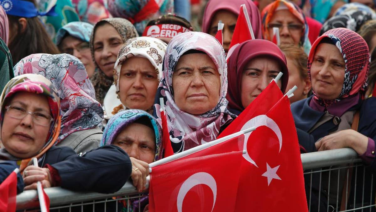 FILE - In this May 30, 2015, file photo, supporters of Turkey's president, Recep Tayyip Erdogan, and prime minister and leader of the Justice and Development Party (AKP), Ahmet Davutoglu, some holding Turkish flags, wait for their appearance in Istanbul during a rally to commemorate the anniversary of city's conquest by the Ottoman Turks. As extremist violence and political uncertainty cast a shadow over Turkey, voters are looking for the parliamentary election to usher in stability. (AP Photo/Lefteris Pitarakis file)