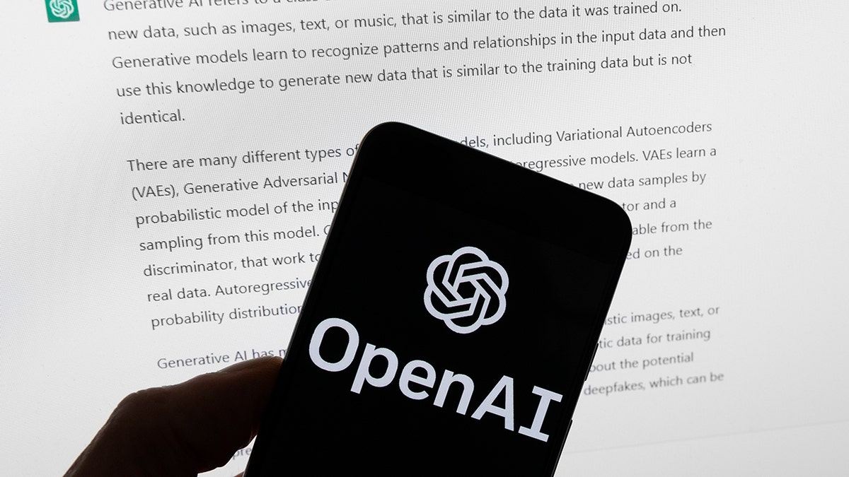 OpenAI logo displayed on a mobile phone in front of a computer screen showing ChatGPT output