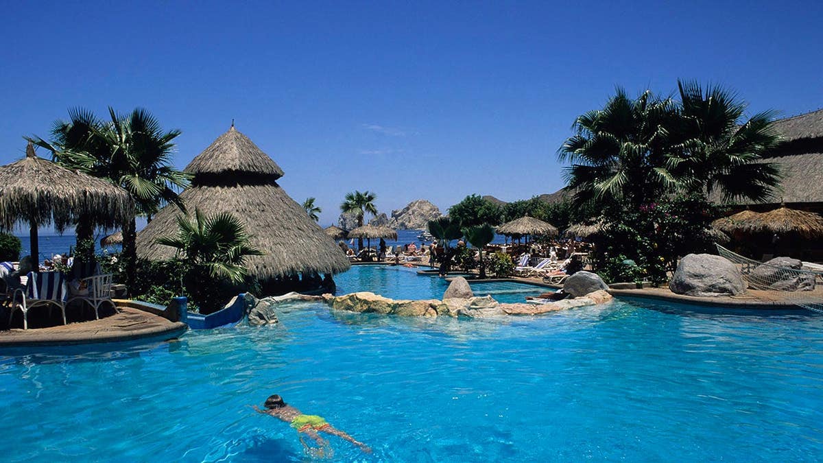 Child swimming in a blue resort pool.
