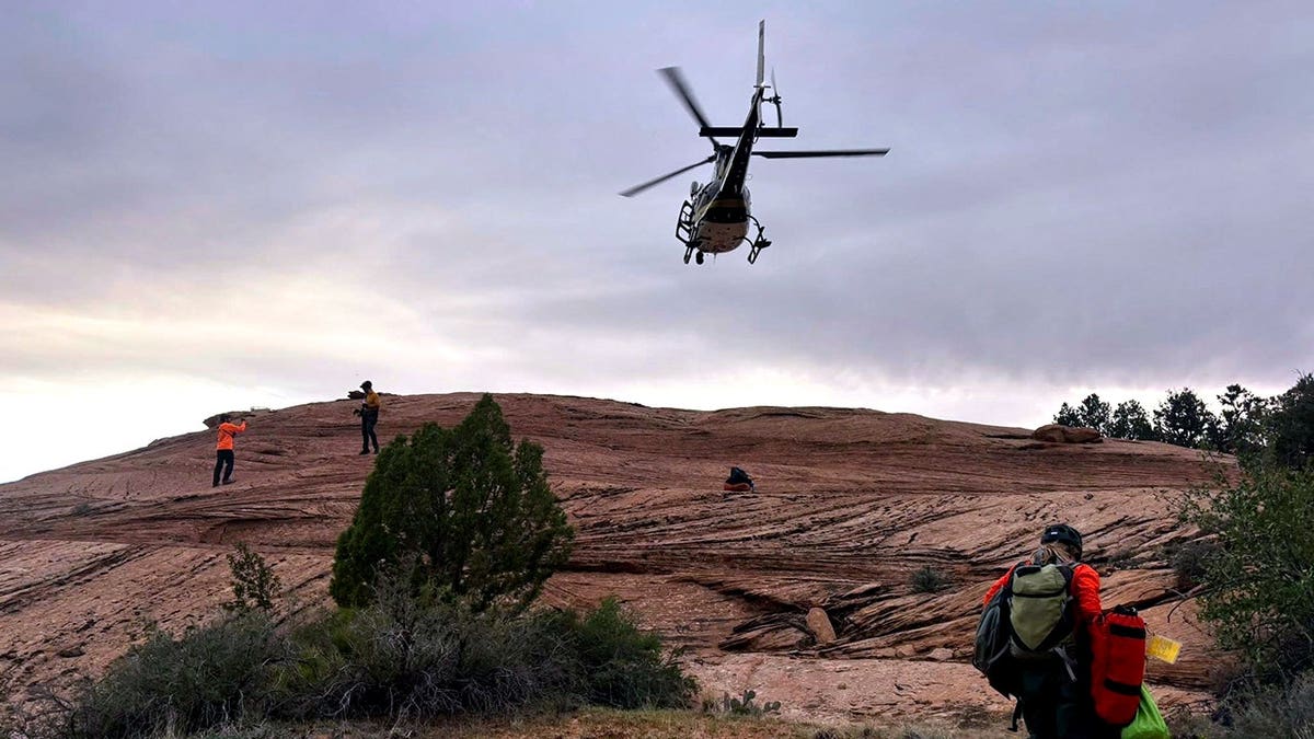 helicopter flying overhead as rescuers walk on ground