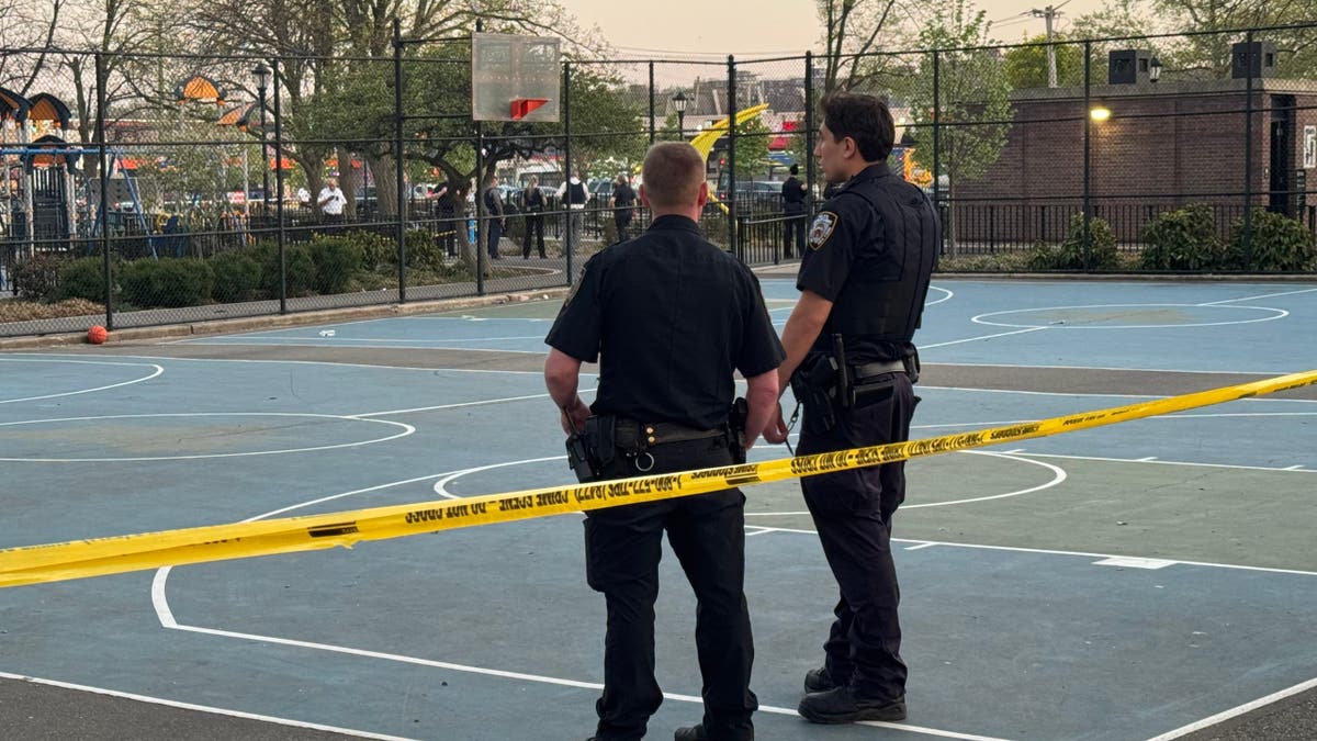 Two police officers at a crime scene on a basketball court