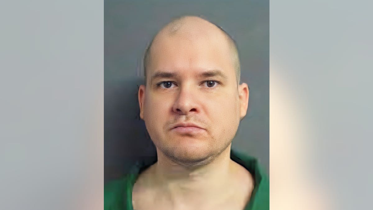 A close-up of Timothy Jones Jr.'s mugshot. He is wearing a green jumpsuit with a shaved head.