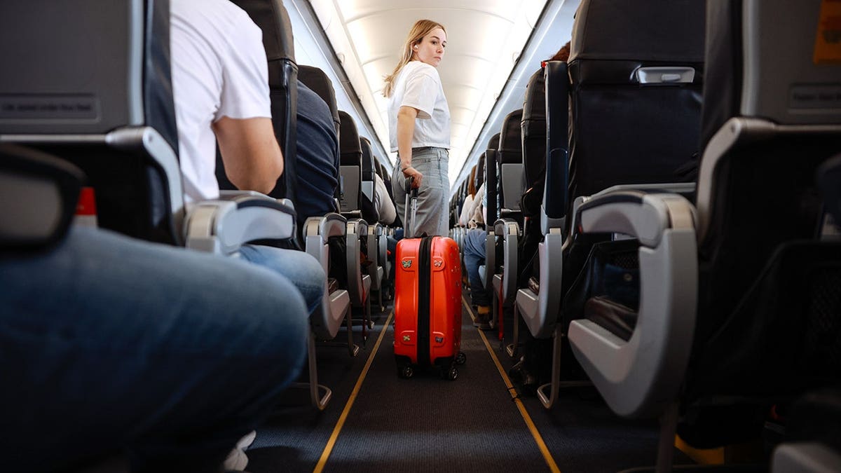 Passengers sitting and standing in airplane aisle during flight