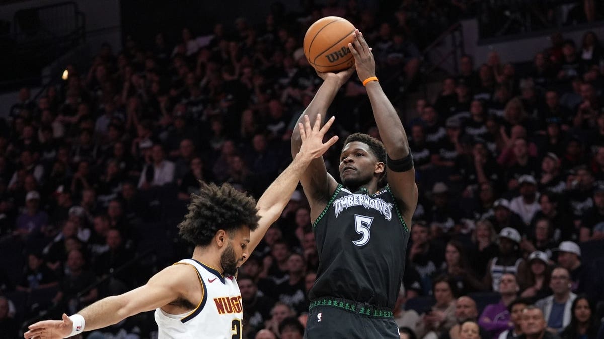Minnesota Timberwolves guard Anthony Edwards shooting over Denver Nuggets guard Jamal Murray in basketball game
