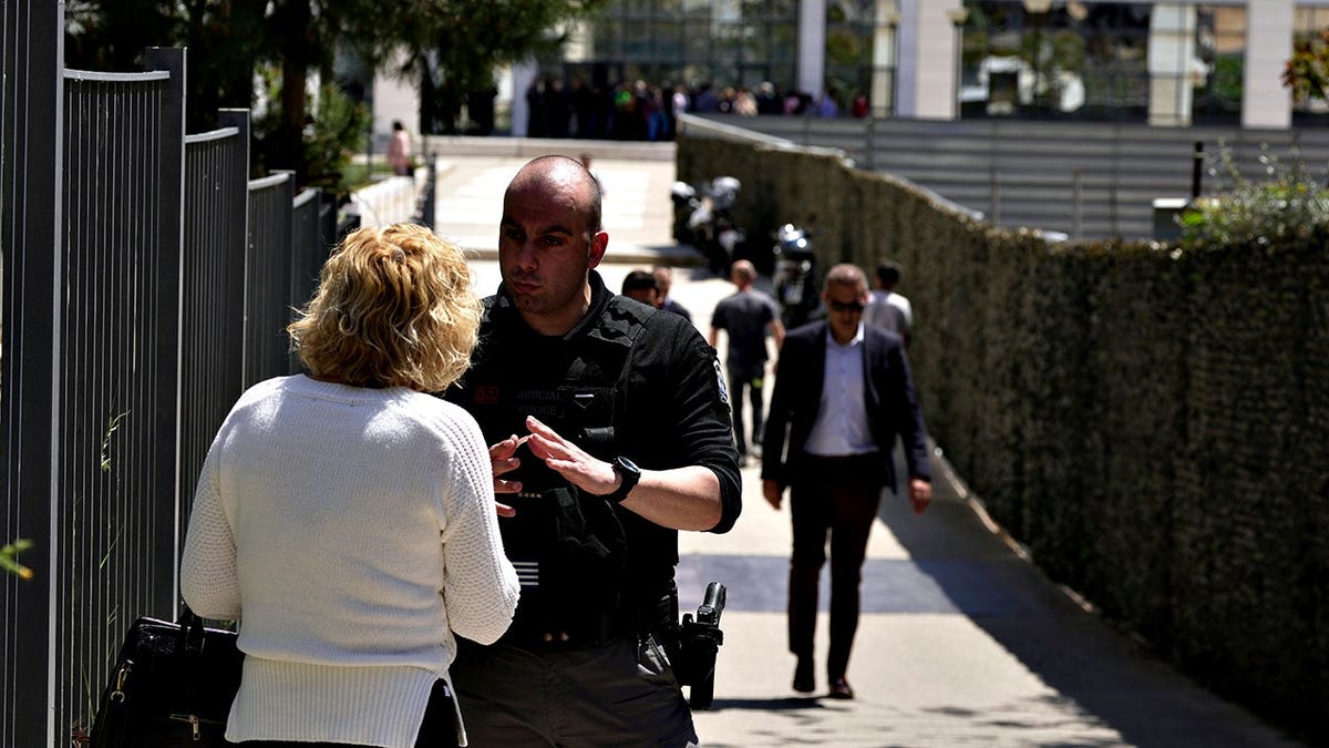 A policeman speaking with a woman outside a courthouse in Athens