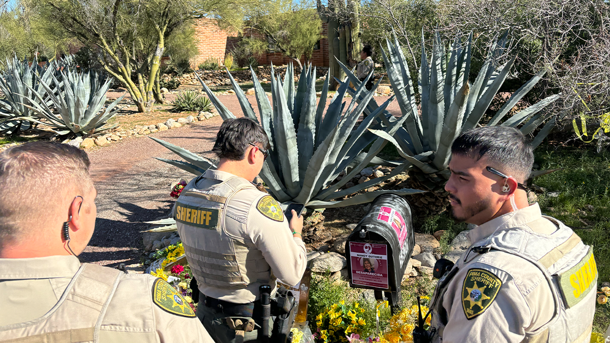 Pima County deputies examining a flyer taped to a mailbox outside Nancy Guthrie's home in Tucson