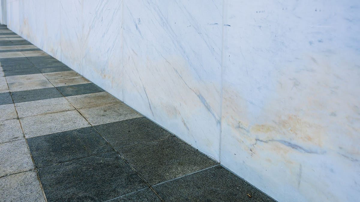 Discolored marble siding with visible staining and corrosion on stone panels