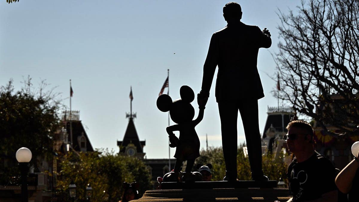 Statue of Walt Disney holding Mickey Mouse's hand outside Sleeping Beauty Castle at Disneyland