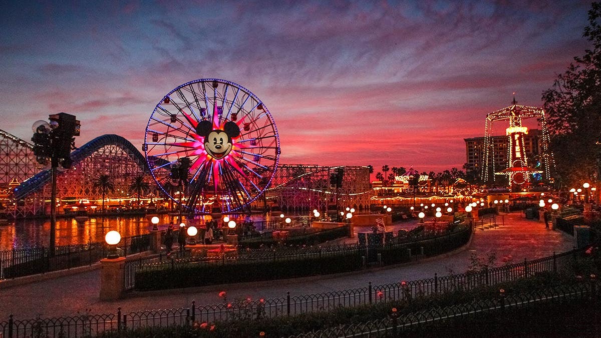 Tourists walking around Disney's California Adventure park at dusk