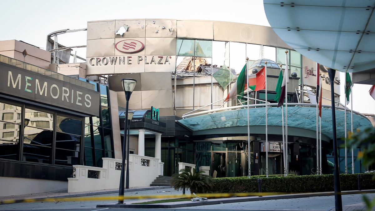 A damaged building with shattered windows and debris stands amid wreckage in Manama after an aerial attack.