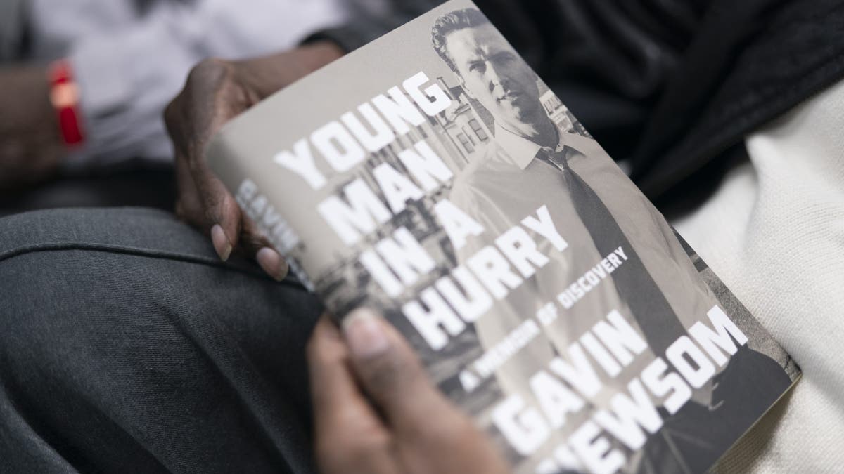 California Gov. Gavin Newsom holding a copy of his memoir Young Man in a Hurry at a South Carolina event