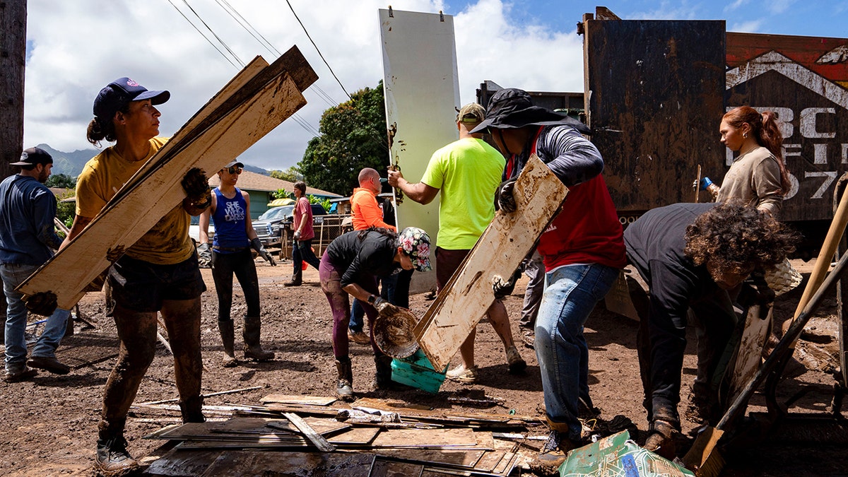 Volunteers loading debris and damaged household items onto a truck in Waialua Hawaii