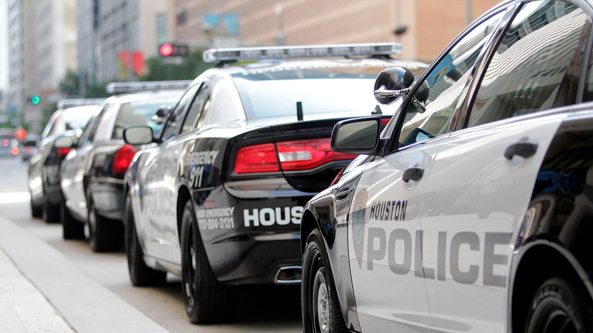 Houston Police Department officers standing near new patrol vehicles outside headquarters