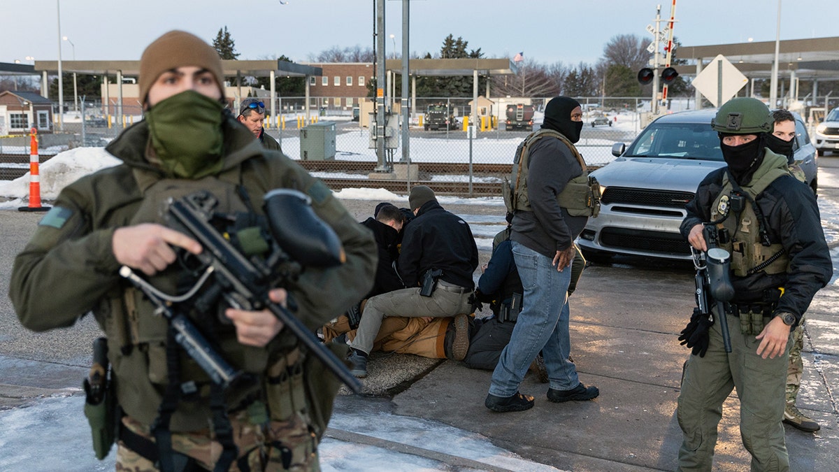 ICE and DHS agents arresting an individual outdoors.