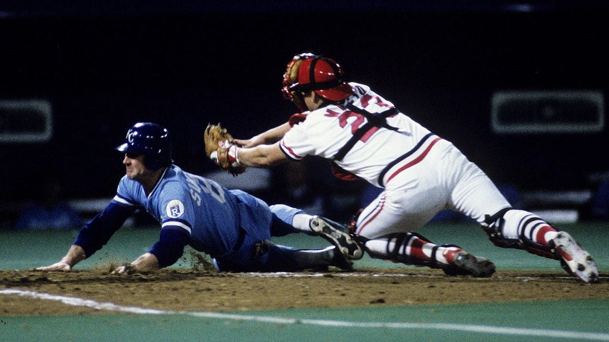Jim Sundberg of the Kansas City Royals scores while Tom Nieto of the St. Louis Cardinals attempts to tag him