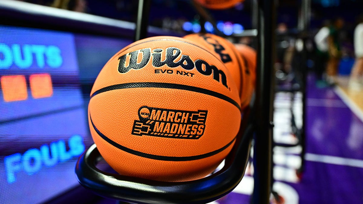 Game ball with March Madness logo on basketball court.