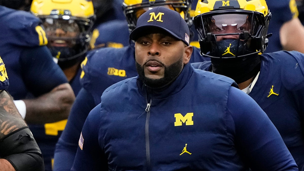 Michigan Wolverines head coach Sherrone Moore leading team onto football field