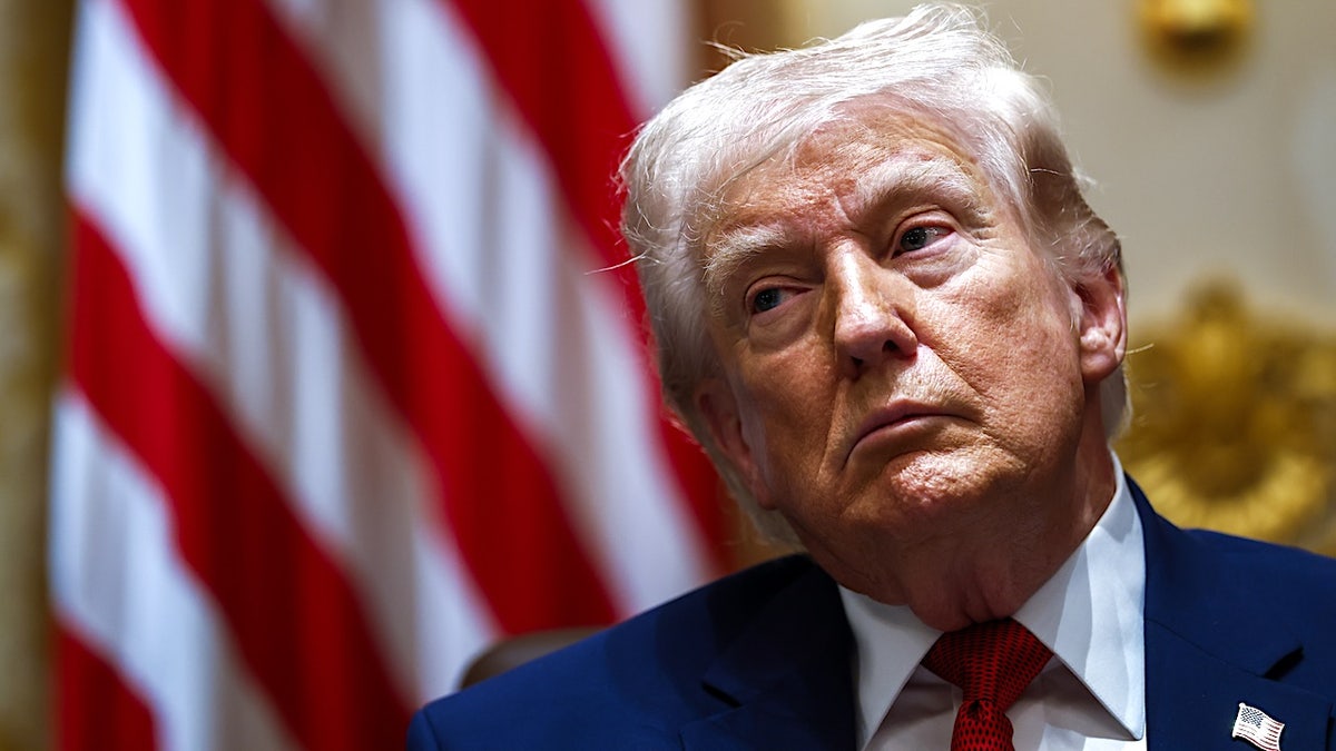 President Donald Trump sitting in front of an American flag during a cabinet meeting