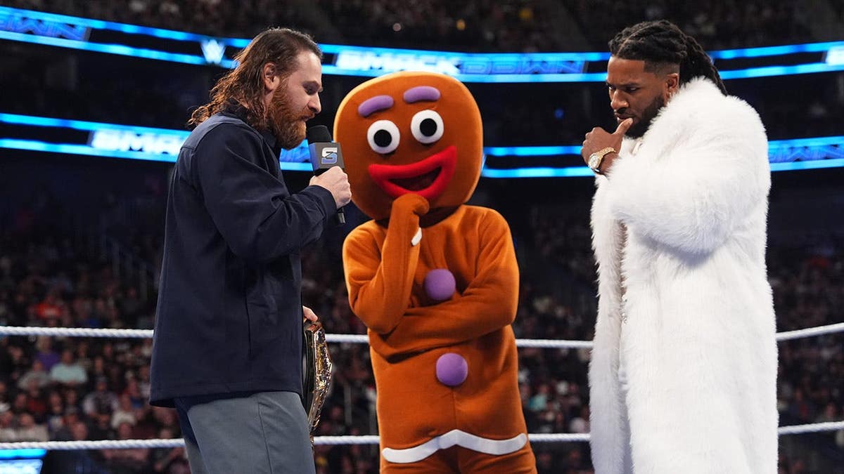 United States Champion Sami Zayn confronts Trick Williams with a gingerbread man character looking on at T-Mobile Arena