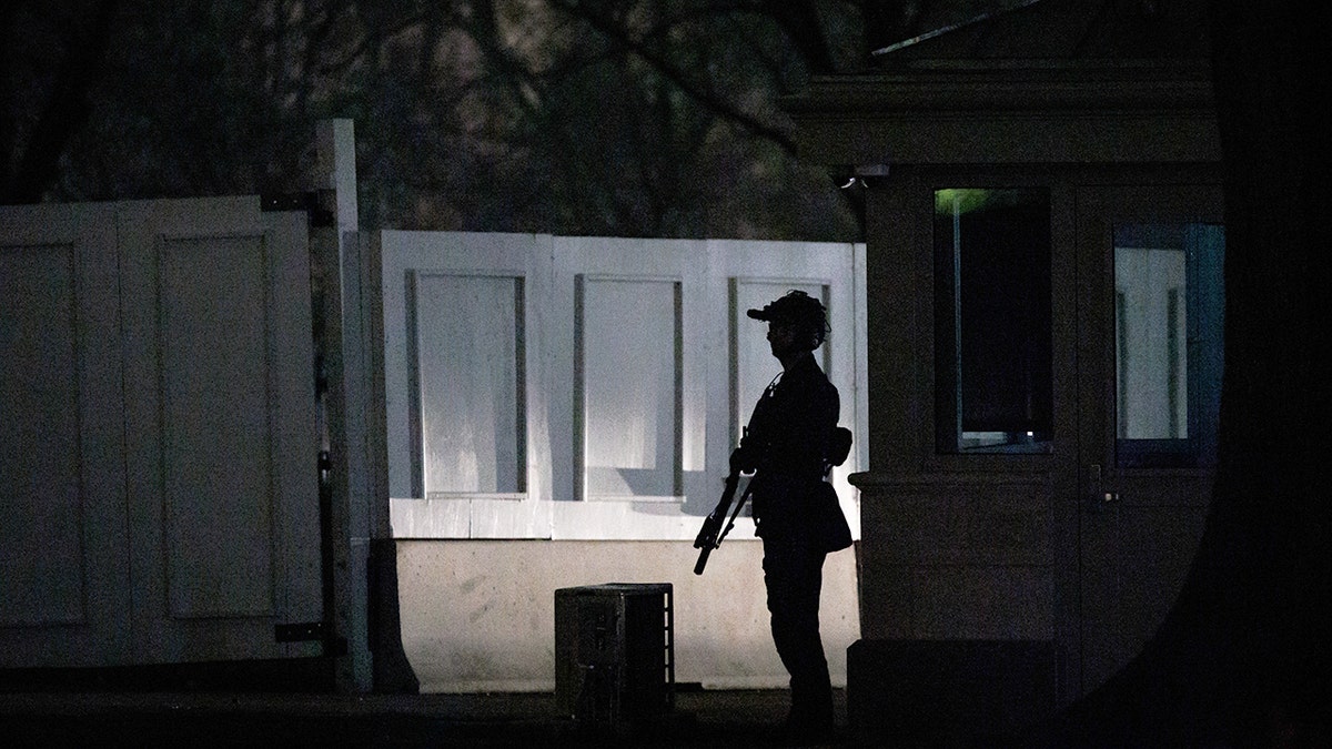A US Secret Service agent in tactical gear standing on the South Lawn of the White House