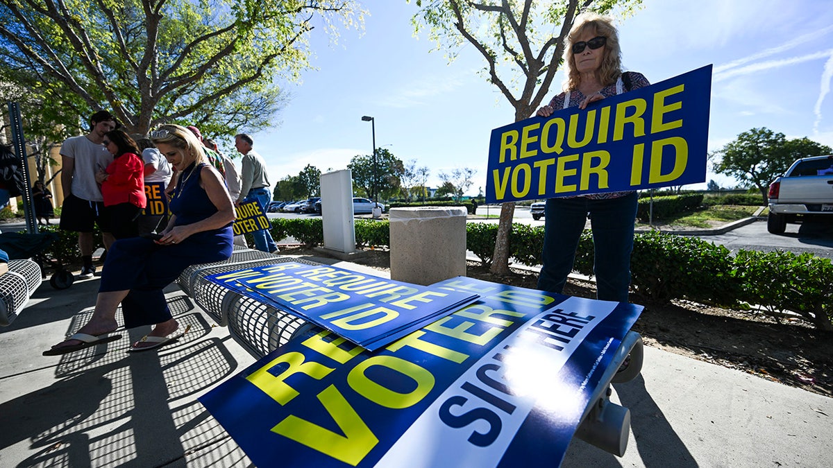 A volunteer picking up a Require Voter ID sign at a press conference in Riverside, California
