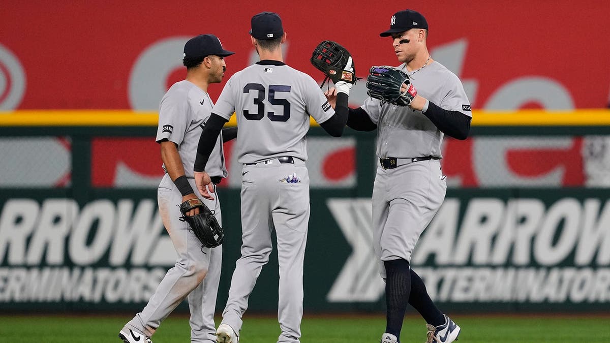 New York Yankees players Trent Grisham, Cody Bellinger, and Aaron Judge celebrating on the field