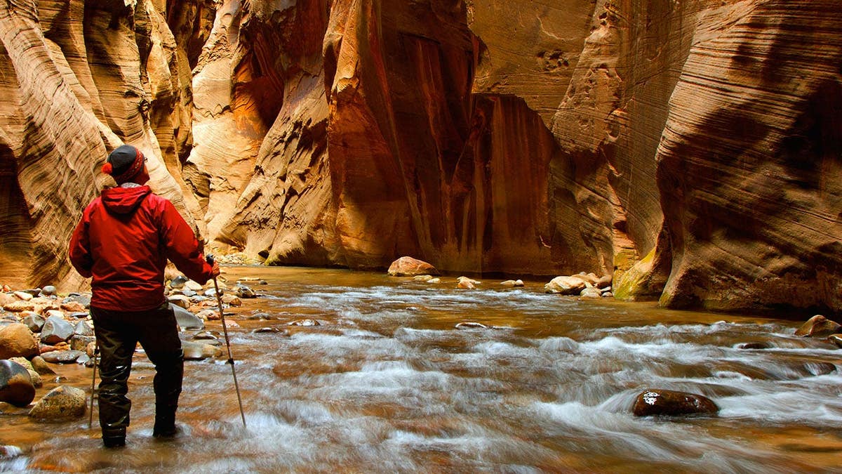 A man hiking into the narrows in Zion National Park Utah