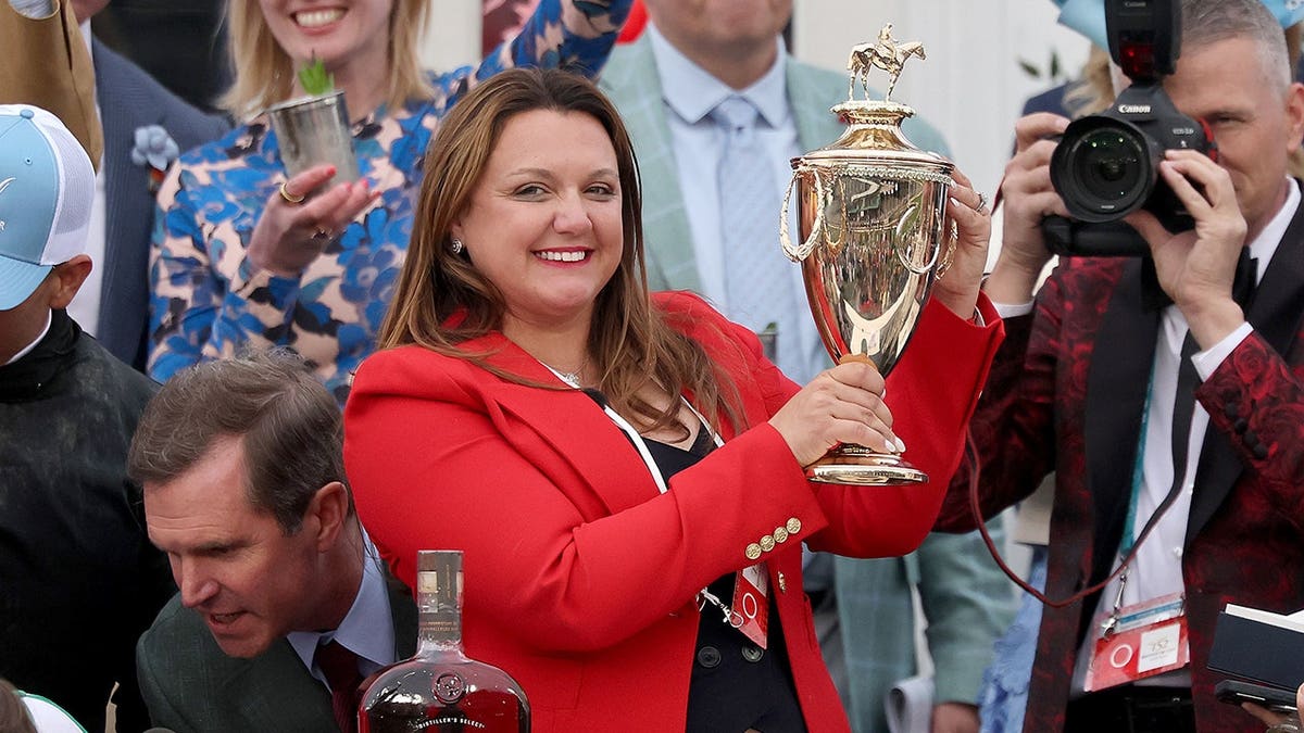 Cherie DeVaux holding trophy in winner's circle at Churchill Downs
