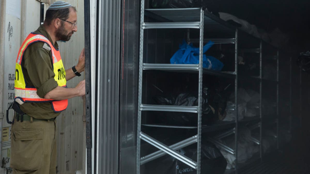 A soldier of the Military Rabbinate unit opens a container with bodies at a military base in Ramle