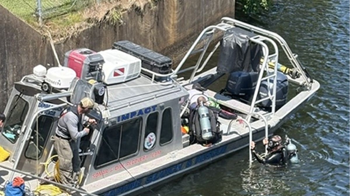 Members of the Gulf Coast Regional Maritime Response and Render-Safe Team fish an IED out of the Converse Reservoir in Mobile, Alabama.