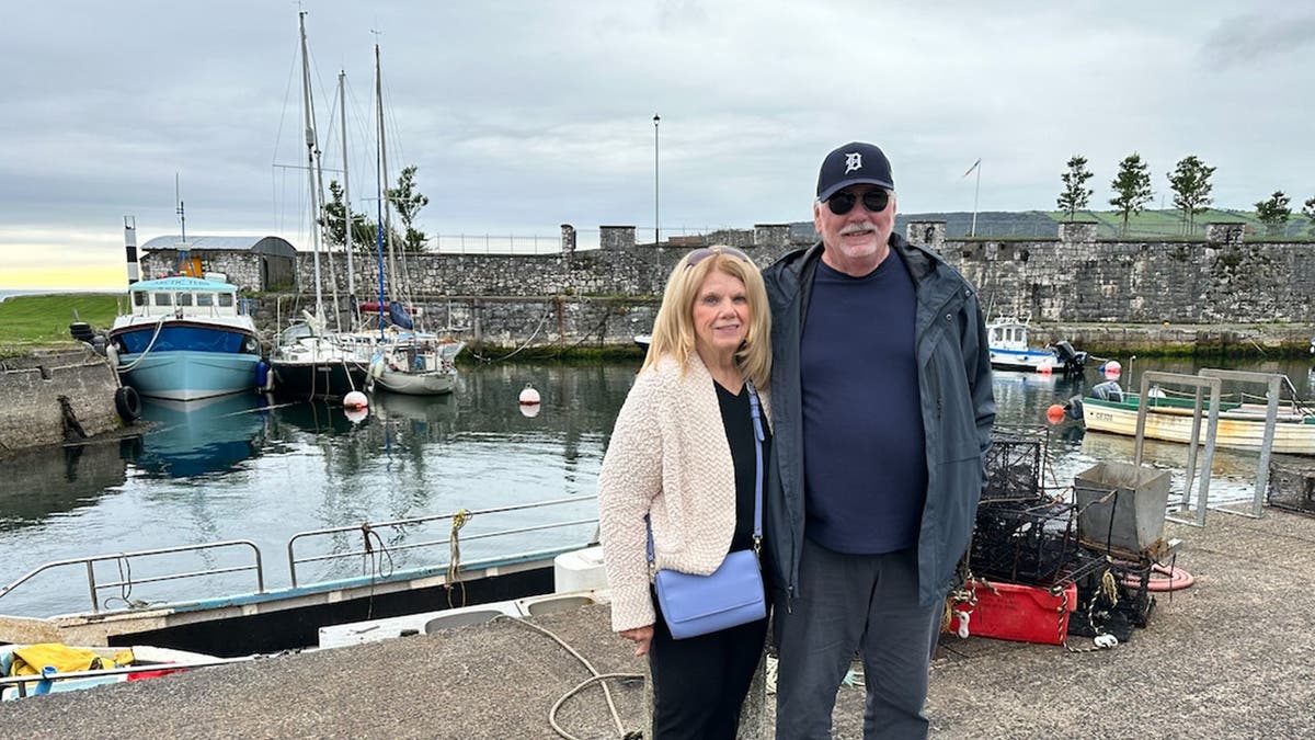 Linda seen on left of Lloyd with the both of them standing in front of a marina.