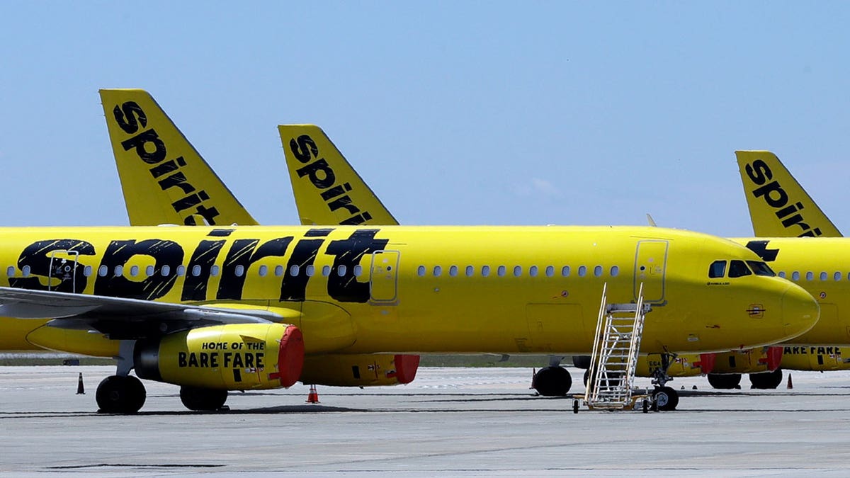 A line of Spirit Airlines jets parked on the tarmac at Orlando International Airport