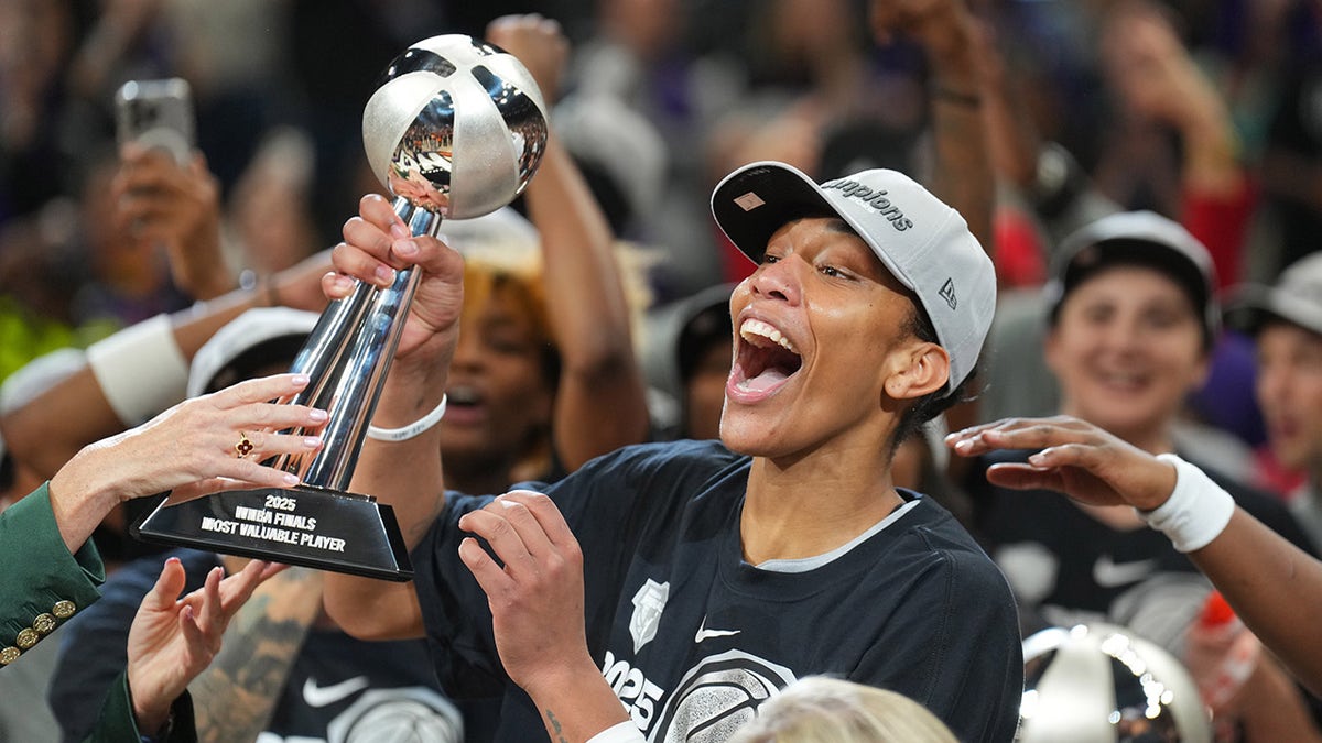 A'ja Wilson holding the WNBA Finals MVP trophy celebrating with teammates